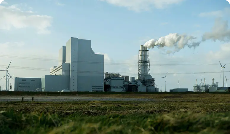 På bilden ser vi en fabrik där det kommer rök ur en av skorstenarna.